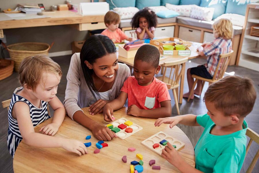 Childcare professional supporting pupils with educational shapes